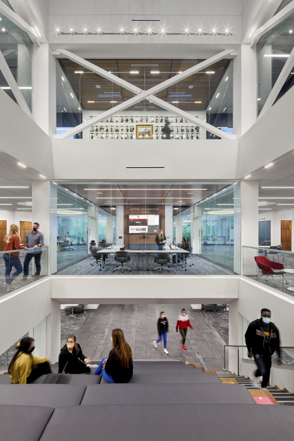 Triple height view with learning stairs, meeting space on second floor, and additional learning space on top floor with white walls and large structure exposed