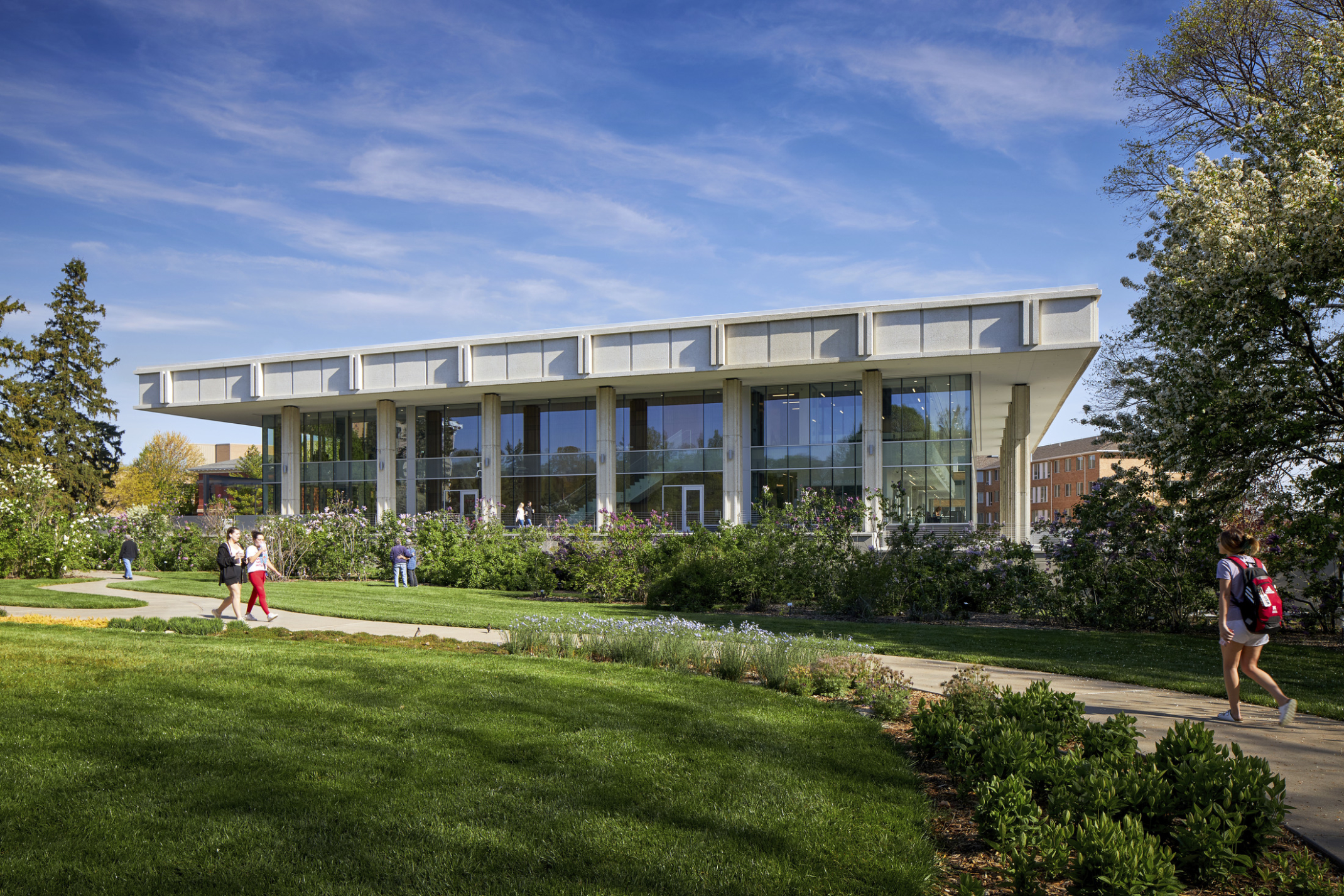 Exterior of two story building with glass windows and cement overhang roof with columns UNL Dinsdale Family Learning Commons.