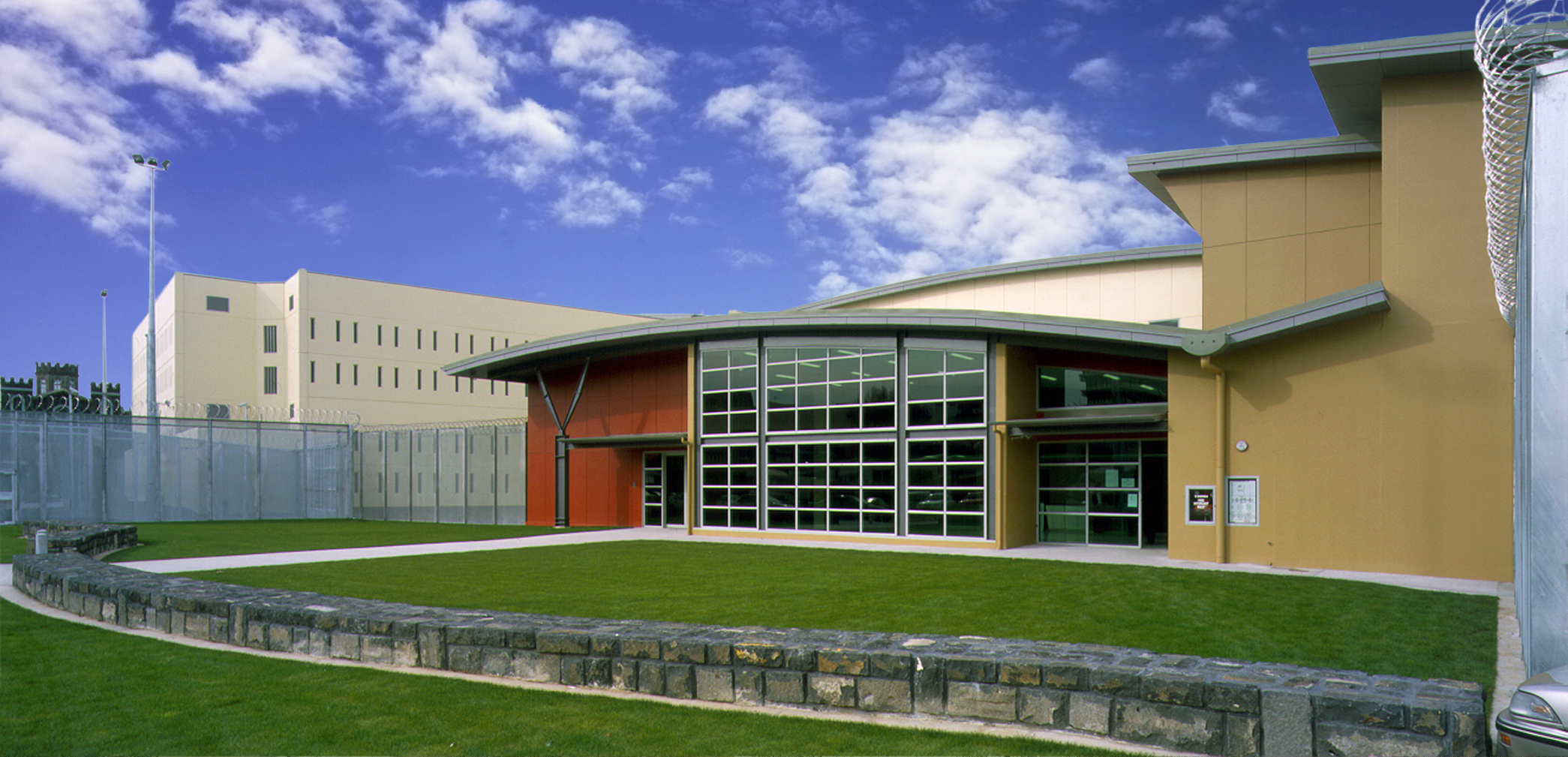 Front entryway with curved roof and double height windows overlooking grass area at Auckland Central Remand Centre. Front entryway with curved roof and double height windows overlooking grass area at Auckland Central Remand Centre.