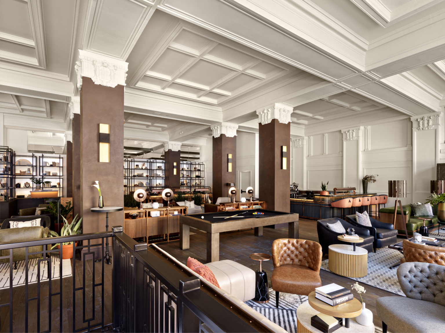 a hotel lobby with white plaster and millwork, billiard tables, and plush leather leather upholstered furniture