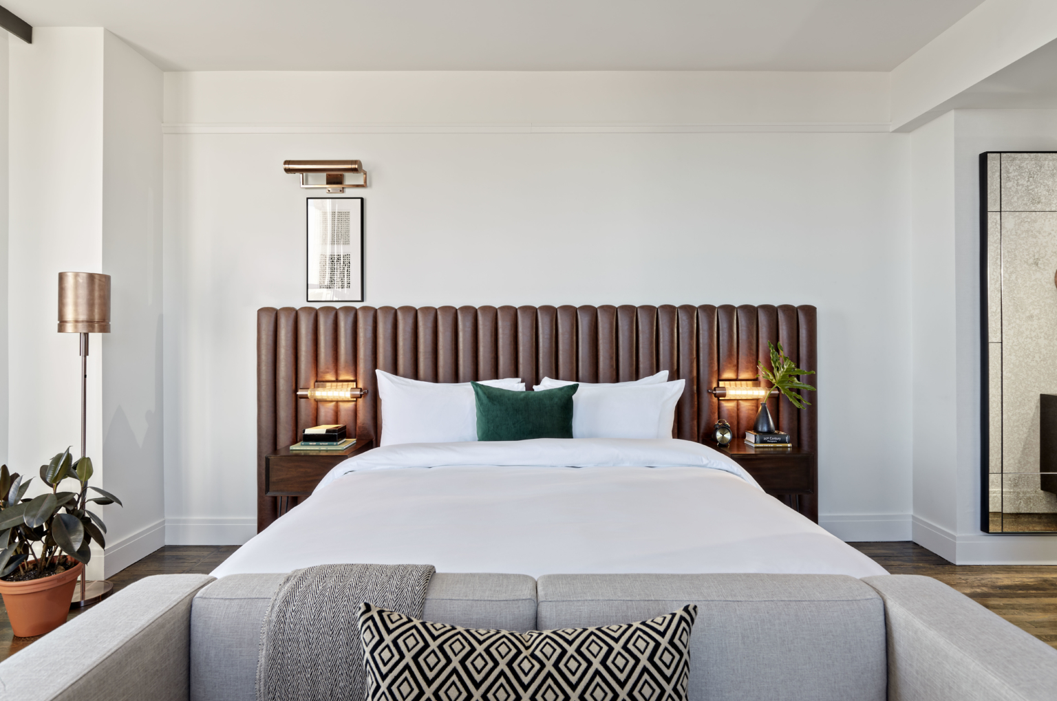 a hotel guest bed with a leather upholstered headboard and white linens a hotel guest bed with a leather upholstered headboard and white linens
