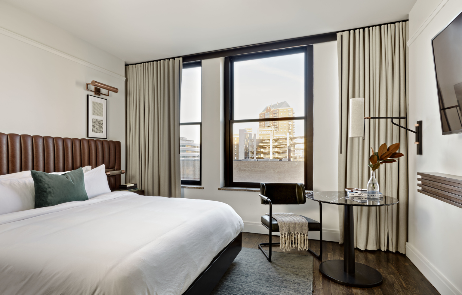 a hotel guestroom with white linens and a brown leather headboard