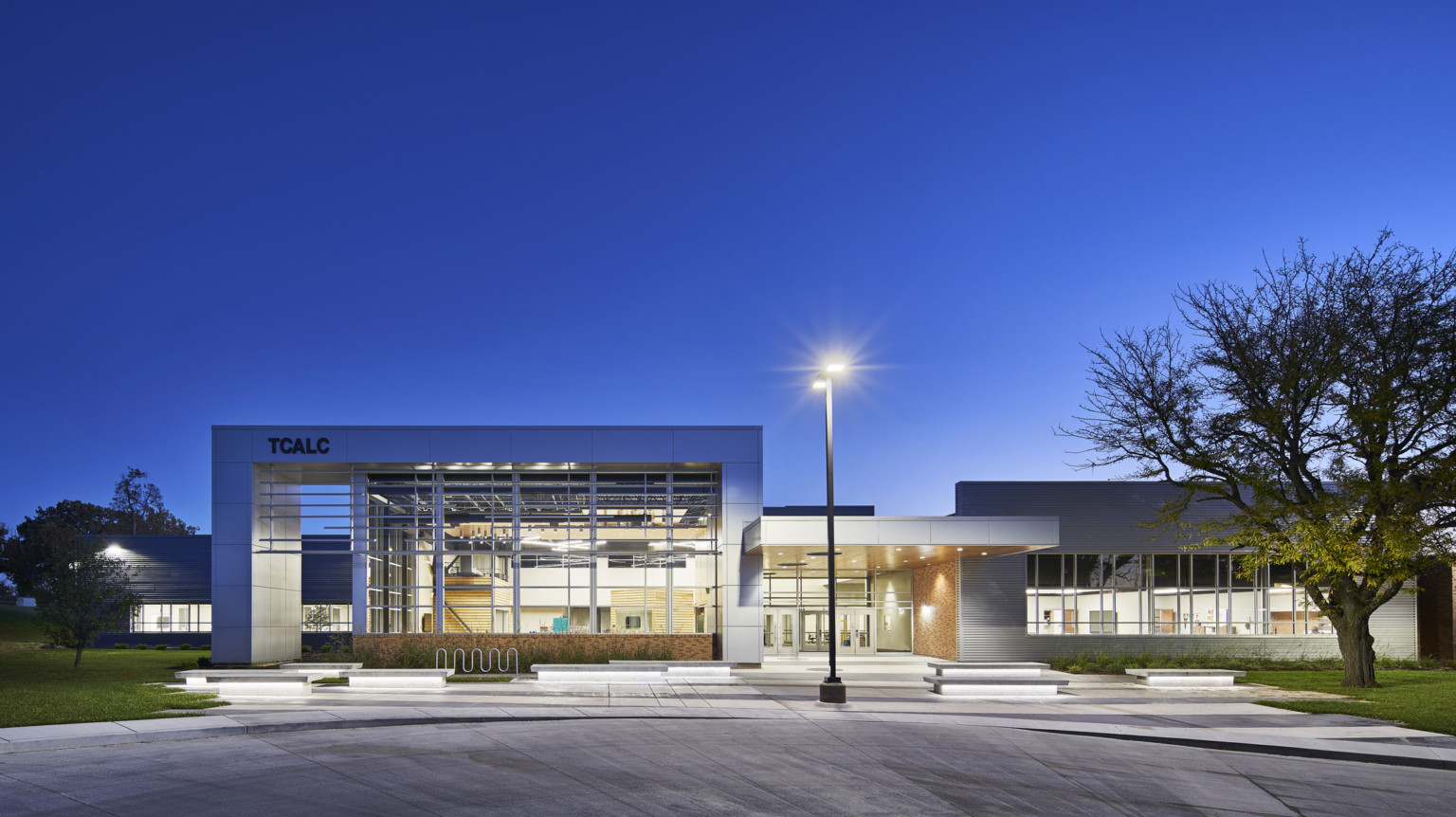 evening exterior view of school with floor to ceiling windows and lighting at TCALC evening exterior view of school with floor to ceiling windows and lighting at TCALC