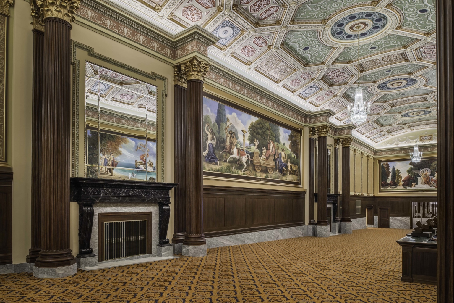 a carpeted hallway with corinthian columns and colorful ceiling frescoes in the ohio theater lobby