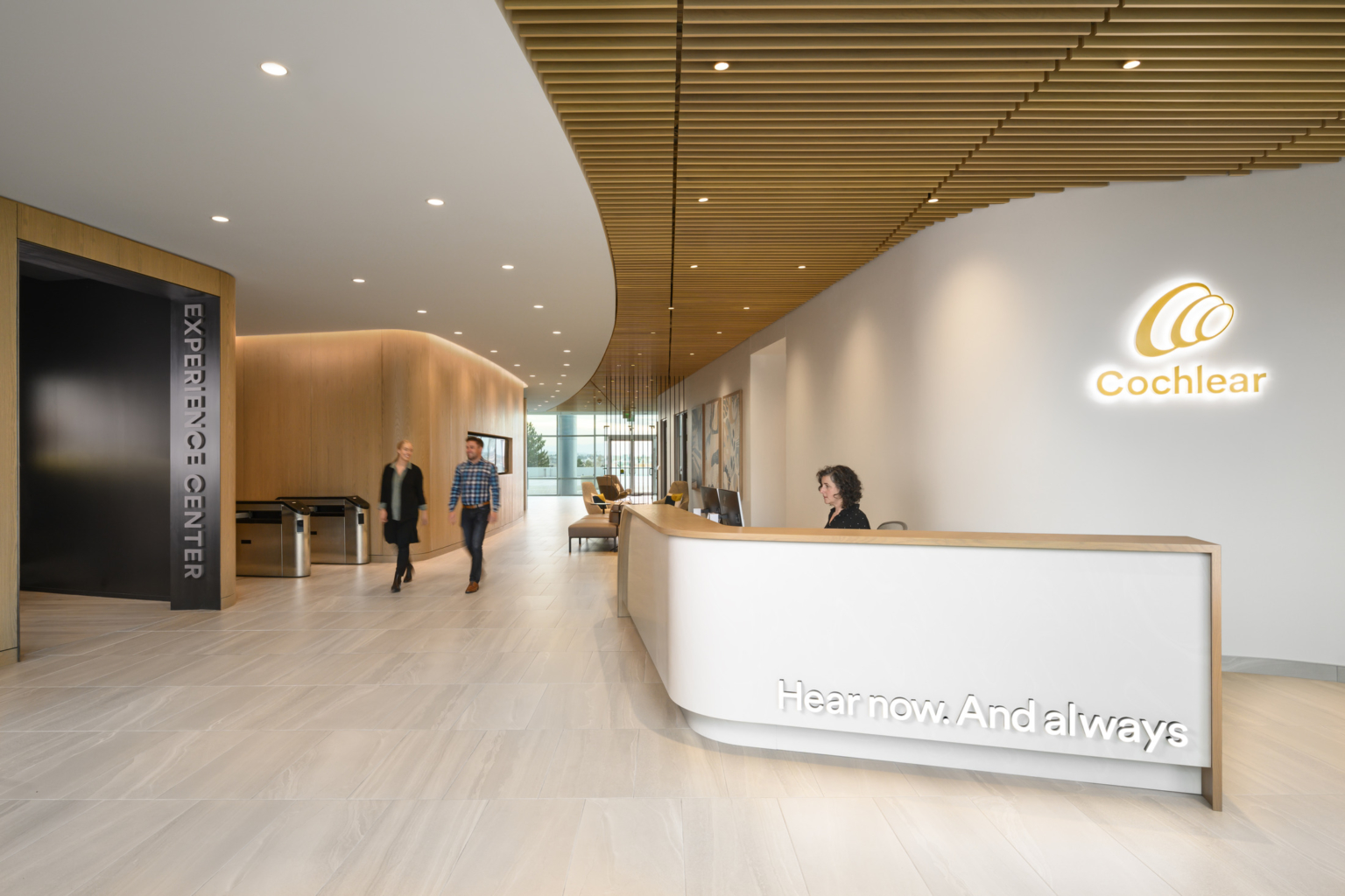 white reception desk under a sculptural white and wood slat ceiling