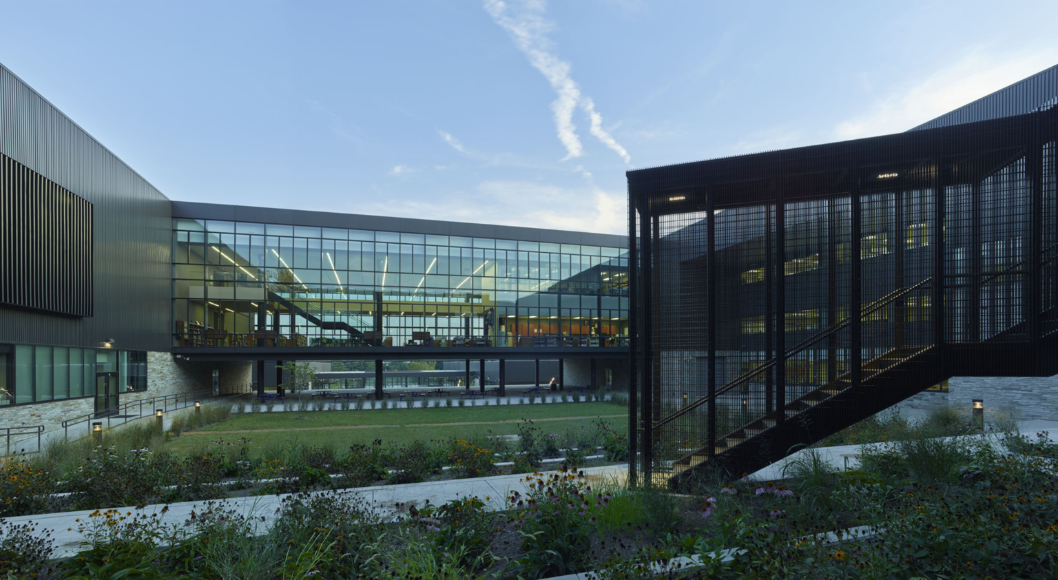 Central green area with glass skyway connecting buildings at Fayetteville High School.