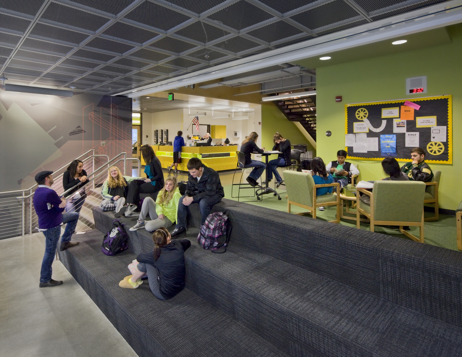 Grey step seating in transition area with green accent wall and seating at Marysville Getchell High School.