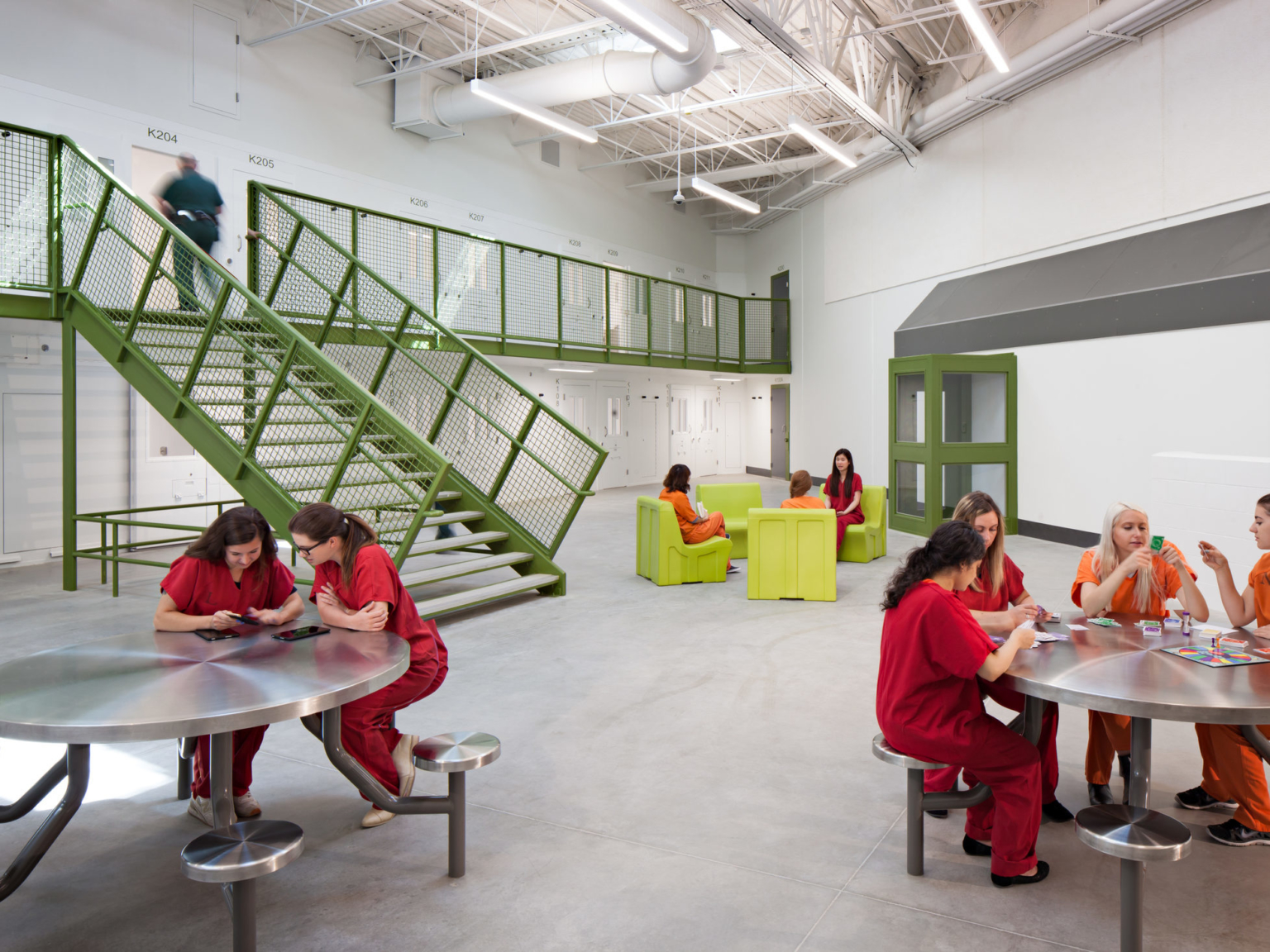 people seated together at tables with green staircase in background