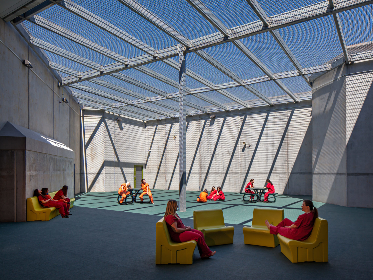 outdoor enclosed recreation area with people seated in yellow chairs