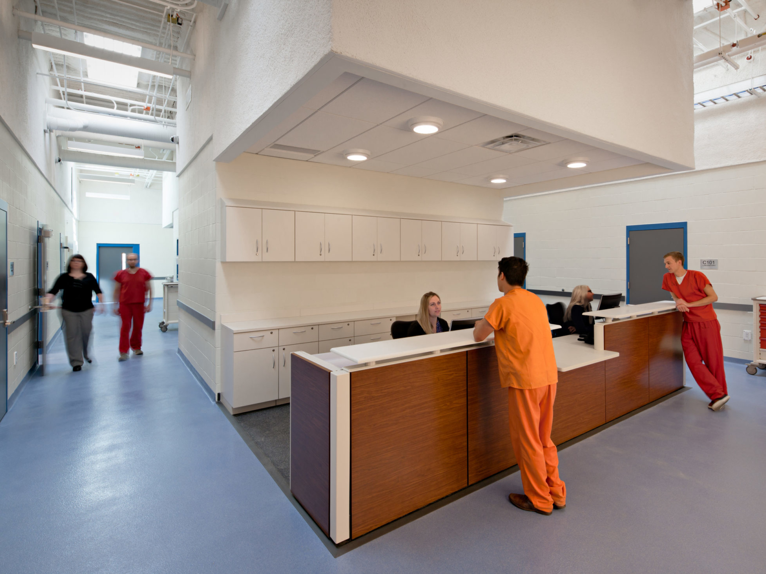 health services area nursing station with seated nurses and standing inmates