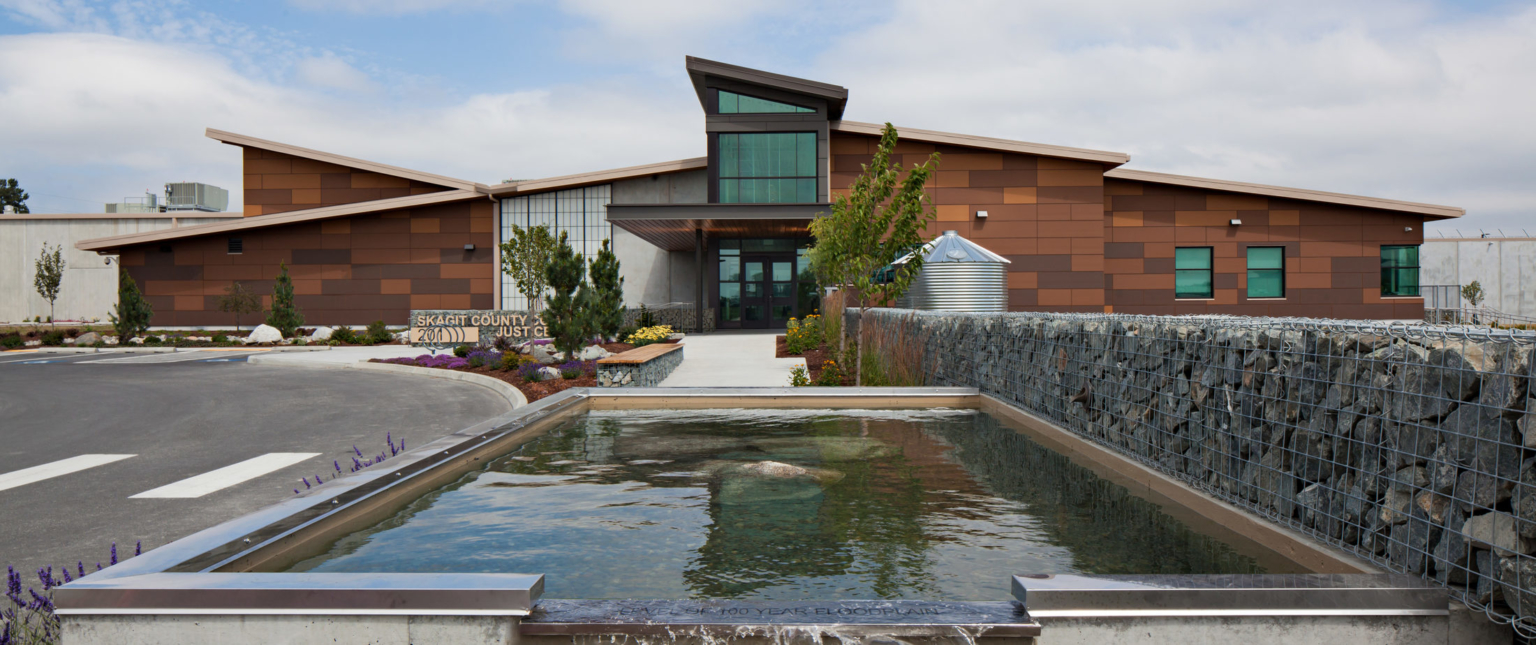 front view of the building with a fountain and gabion wall