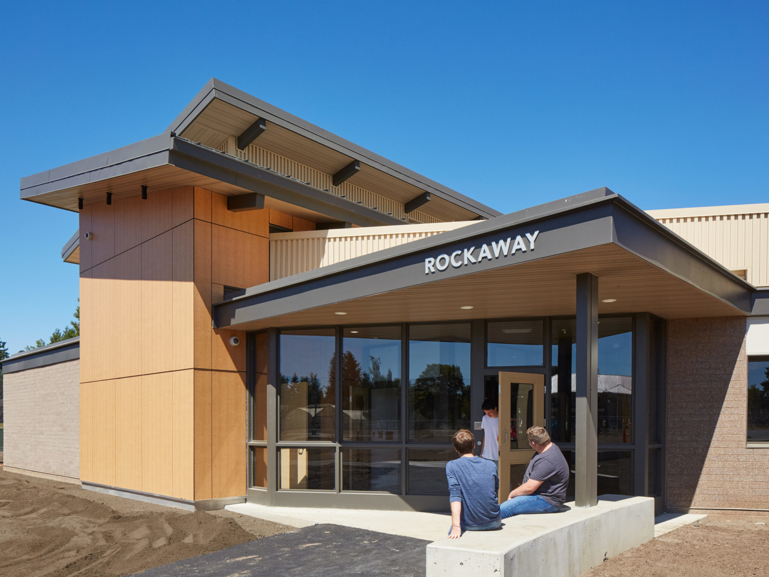 exterior daytime view of rockway building with people sitting by entrance