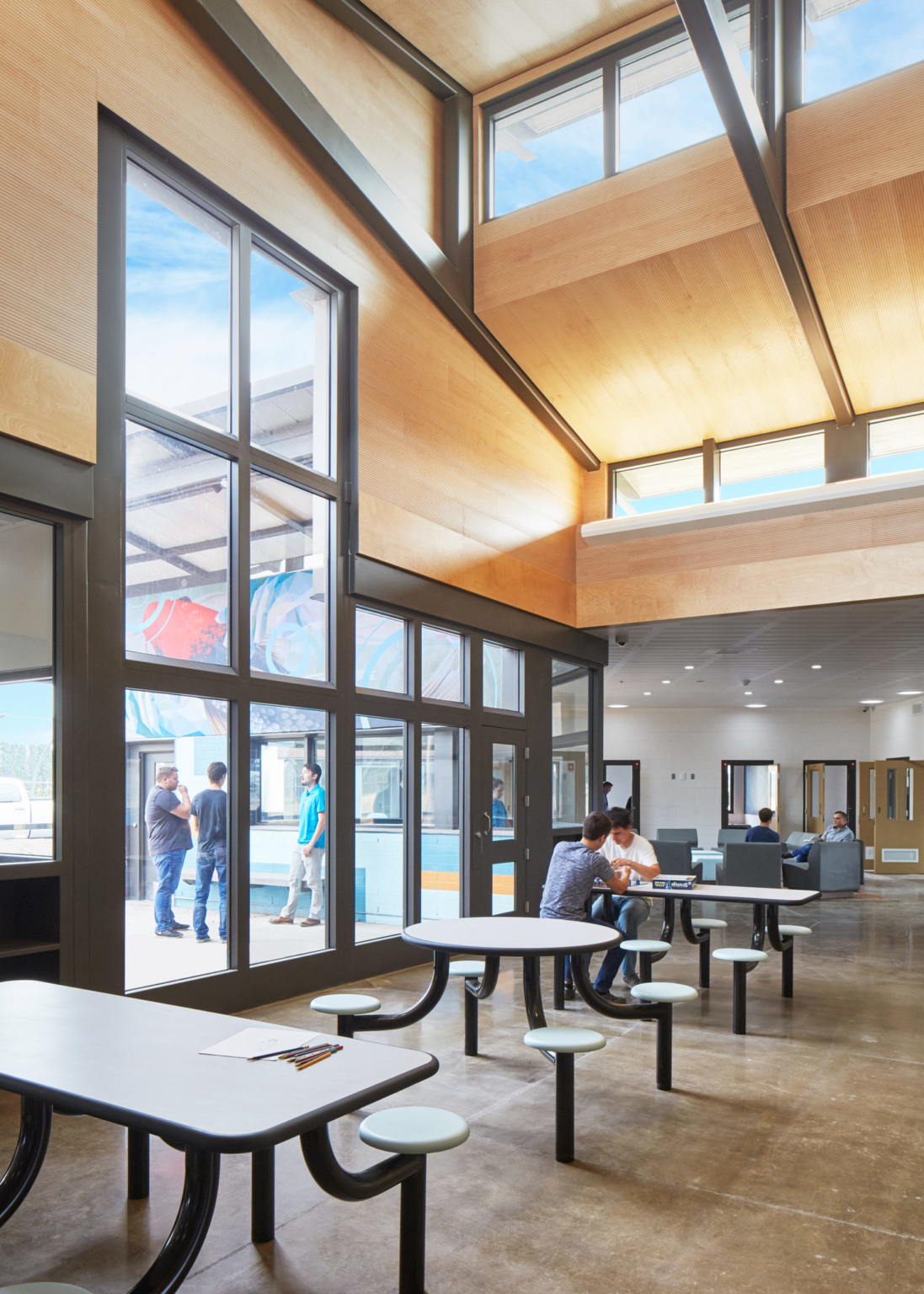 inside a building with tables and chairs with a view through a large window covered wall