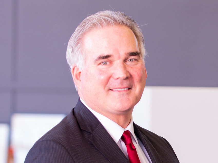 smiling man in a dark suit and a red tie