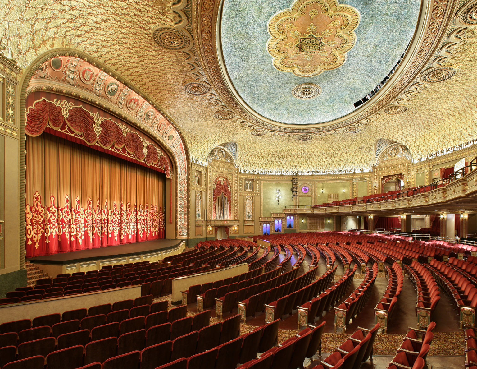 Historic grand theater with red seating, grand ornate archway over stage, red drop curtain, and gold ceiling at the Tennessee Theater Historic grand theater with red seating, grand ornate archway over stage, red drop curtain, and gold ceiling at the Tennessee Theater