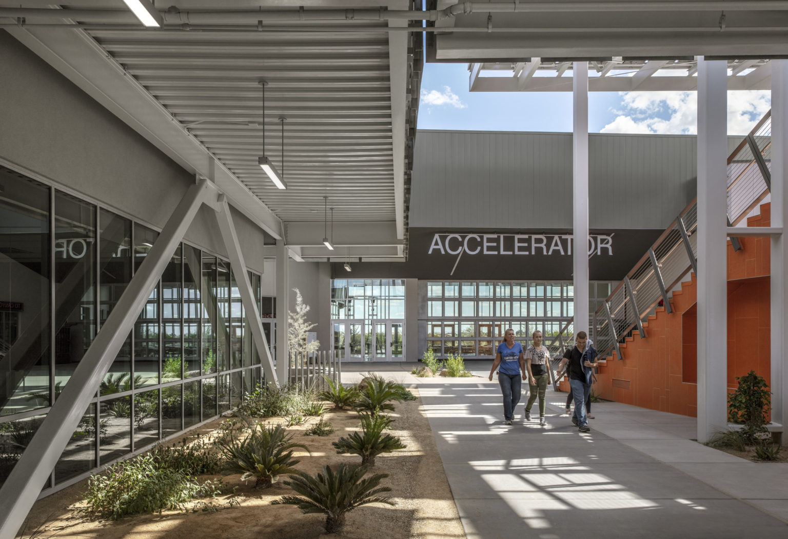 a shaded walkway lined with desert scaping and exposed structural bracing a shaded walkway lined with desert scaping and exposed structural bracing