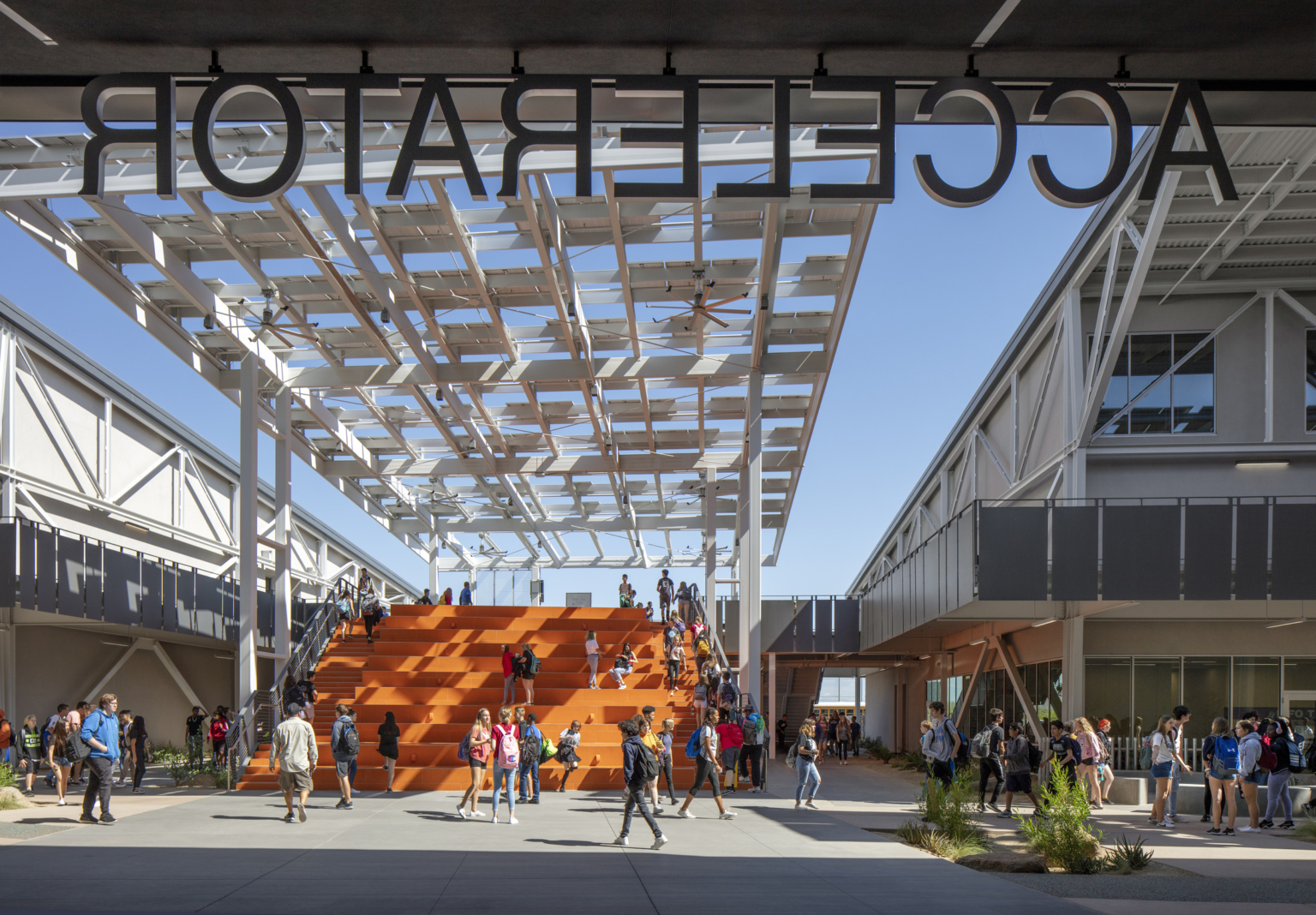 the view from the interior auditorium of the accelerator onto an orange bleacher stair and solar panel canopy