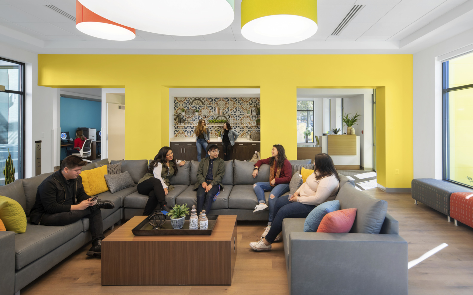 students sitting around a couch with yellow walls and drop pendant lighting for inviting and home away from home environment students sitting around a couch with yellow walls and drop pendant lighting for inviting and home away from home environment