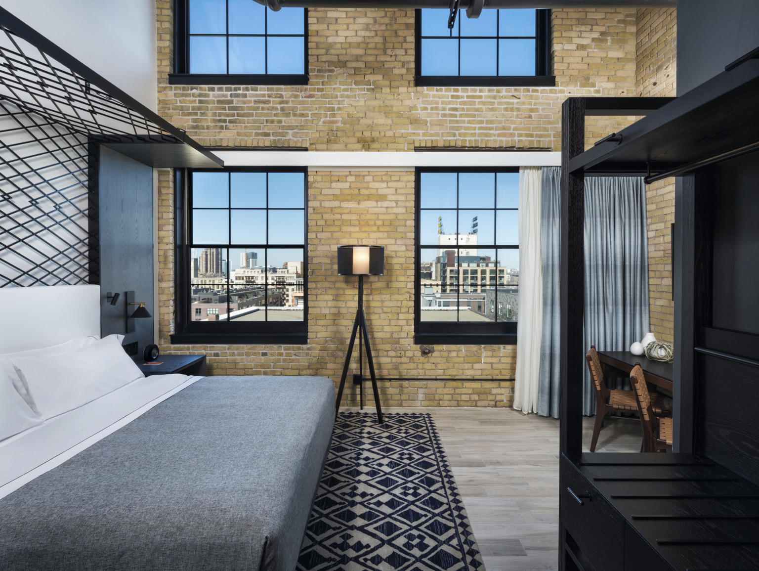 guestroom with detailed canopy above bed, brick walls, blue pattern carpet at the minneapolis mill district hotel