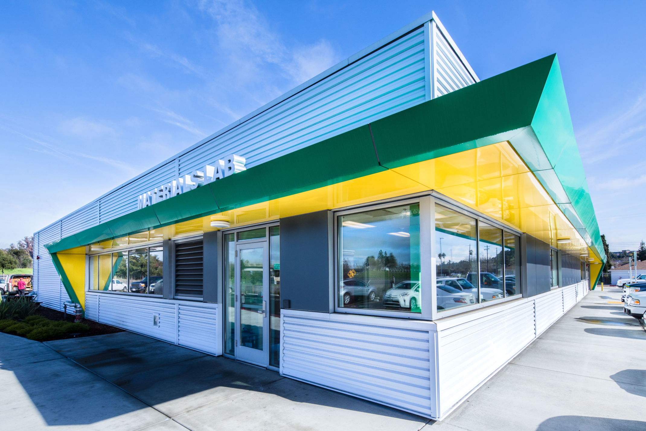 exterior shot of white green and yellow building at an angle with windows along walls exterior shot of white green and yellow building at an angle with windows along walls