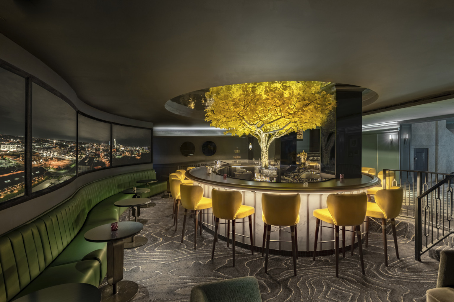 an illuminated yellow tree in the midst of in the round high top seating an illuminated yellow tree in the midst of in the round high top seating