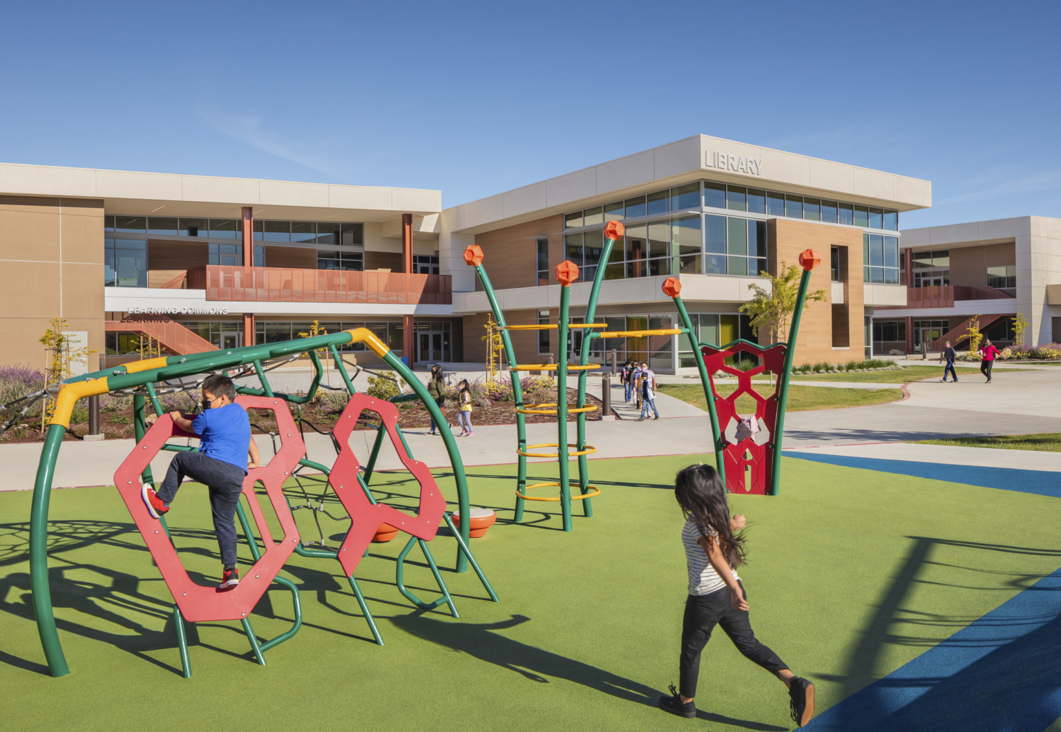 kids playing on colorful playground outside in front of school