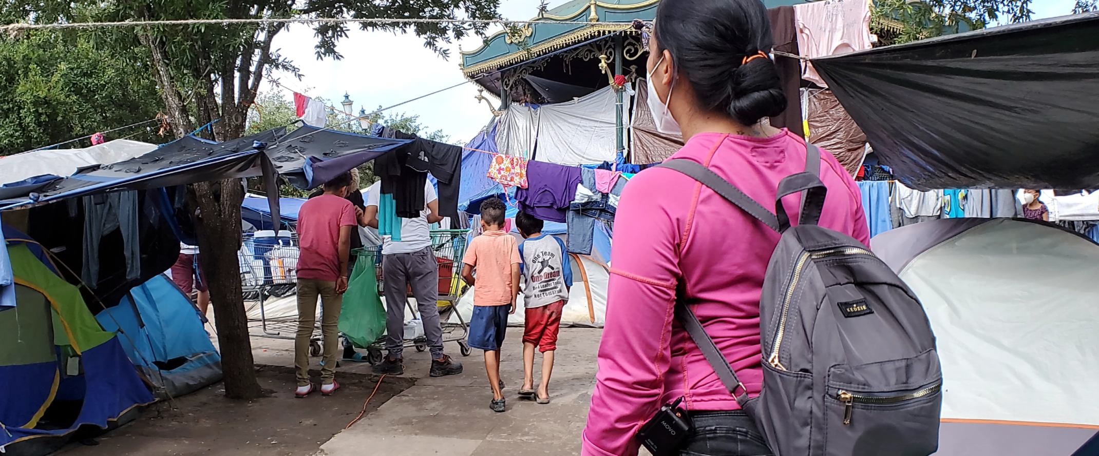 a woman wearing a backpack at a migrant camp in reynosa mexico