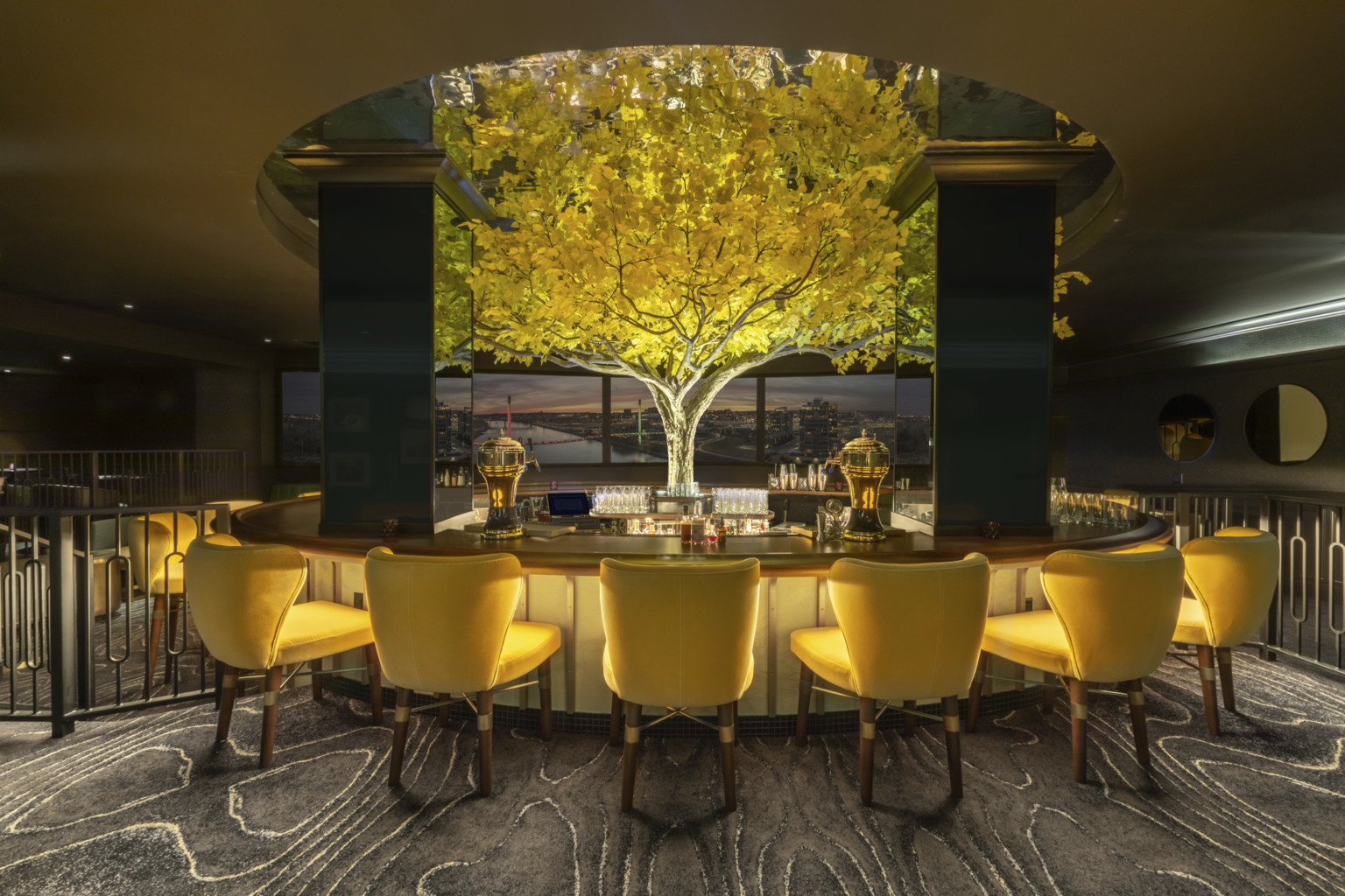 an illuminated yellow tree in the midst of in the round high top seating an illuminated yellow tree in the midst of in the round high top seating