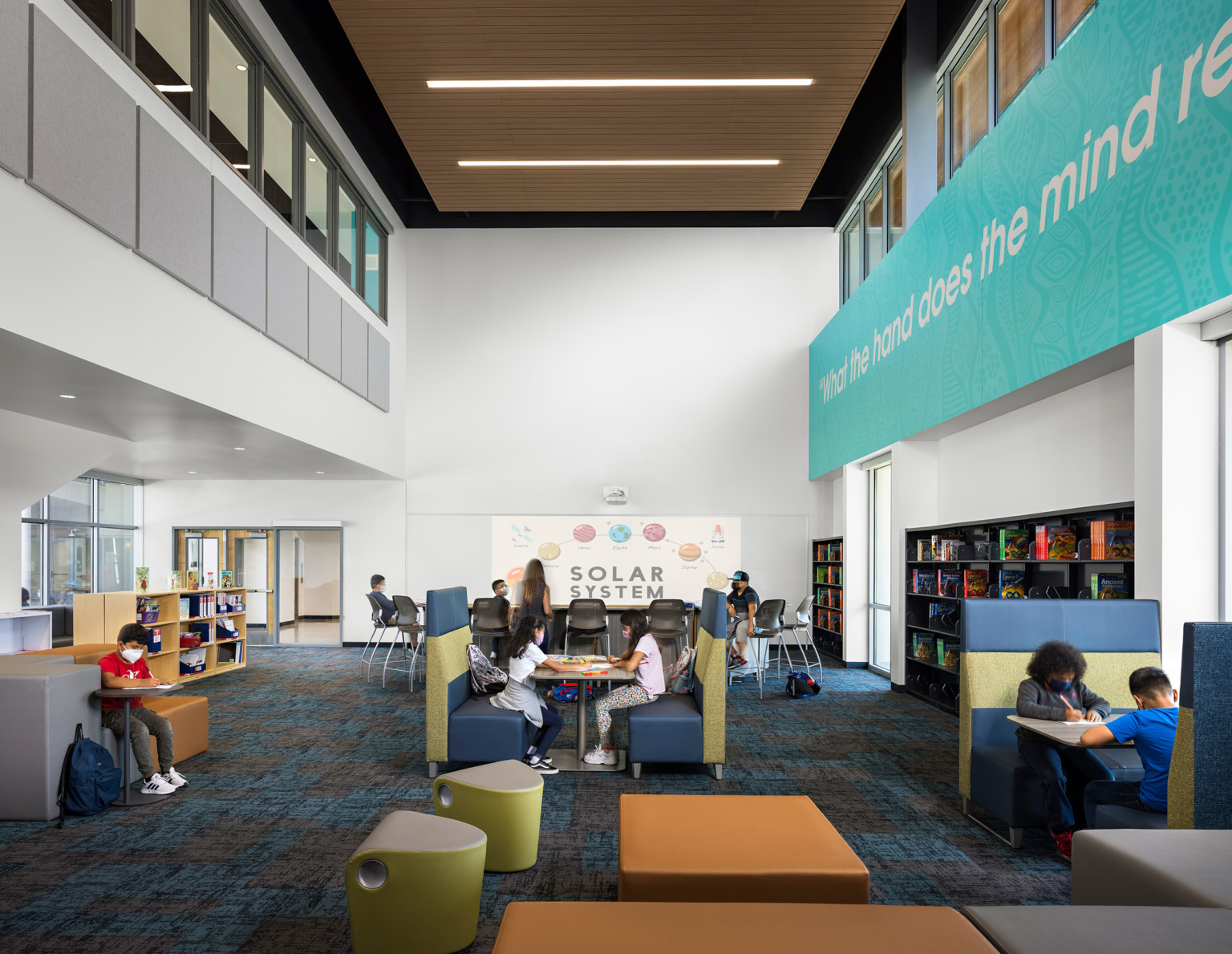 a work area with flexible seating and work areas and super graphics under a mezzanine a work area with flexible seating and work areas and super graphics under a mezzanine