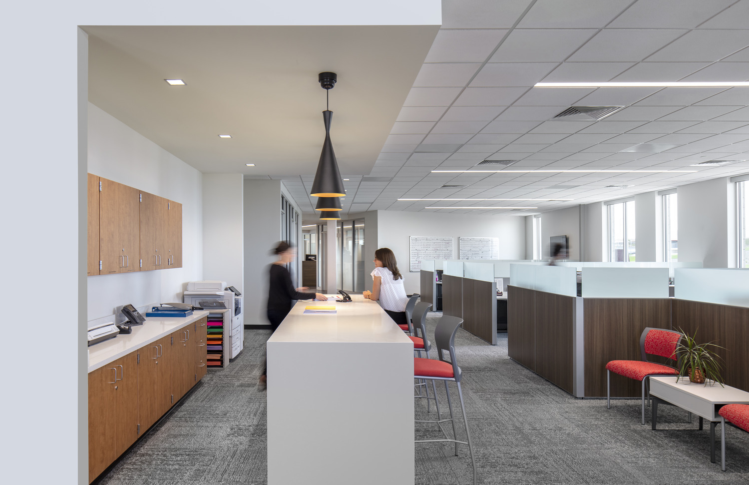 white standing height table under pendant lighting next to work stations and a seating area white standing height table under pendant lighting next to work stations and a seating area