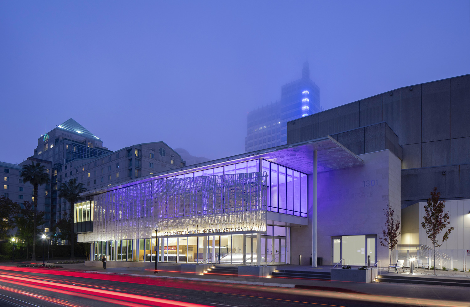Looking from across the street at the exterior of the SAFE Credit Union Performing Arts Center in Sacramento, lit up with purple lights
